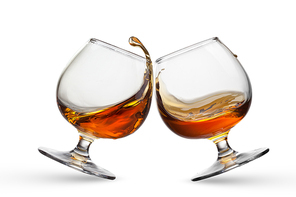 Splash of cognac in two glasses isolated on white