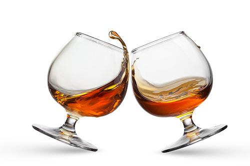 Splash of cognac in two glasses isolated on white