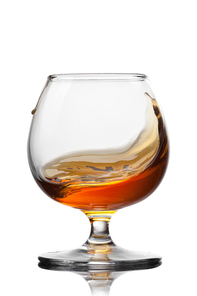 Splash of cognac in glass isolated on white