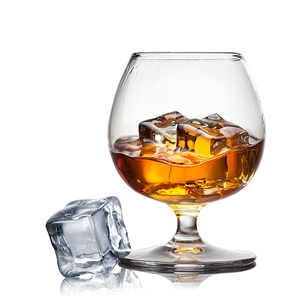 Splash of whiskey with ice in glass isolated on white background