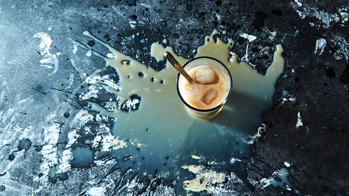 Coffee with milk and ice cubes. A pattern from splashes and drops of coffee on a black concrete background with space for text. Top view