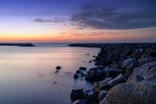 A beautiful sunset on the coast of Rugen Island in Germany long exposure with a rock jetty