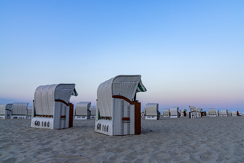 A beautiful sunset and beach evening with white beach baskets on sandy beach