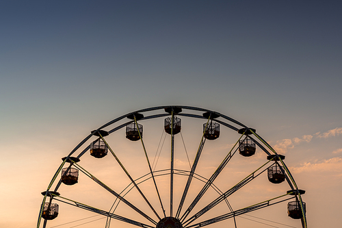 view of a ferris wheel in silhouette at sunset with copy space