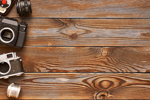 Vintage old 35mm cameras, lenses and light meter on wooden background