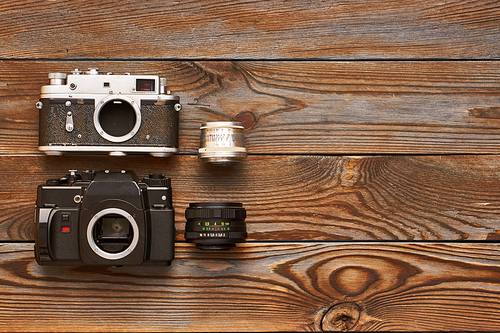 Vintage old 35mm cameras and lenses on wooden background