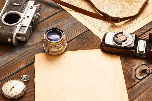 Vintage old 35mm camera, lens and light meter on wooden background with antique XIX century map