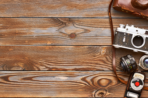 Vintage old 35mm cameras, lenses and light meter on wooden background