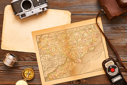 Vintage old 35mm cameras, lenses and light meter on wooden background with antique XIX century map