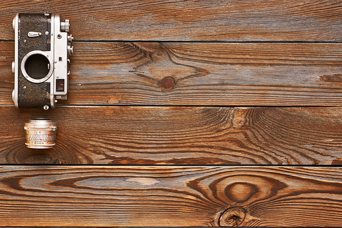 Vintage old 35mm camera and lens on wooden background