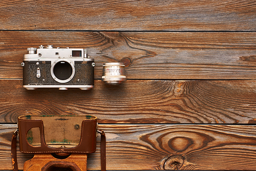 Vintage old 35mm camera and lens on wooden background