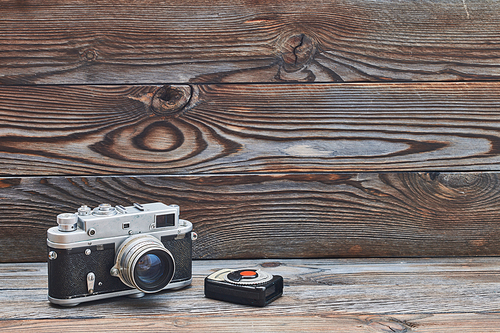 Vintage old retro 35mm rangefinder camera and light meter on wooden background with copy space