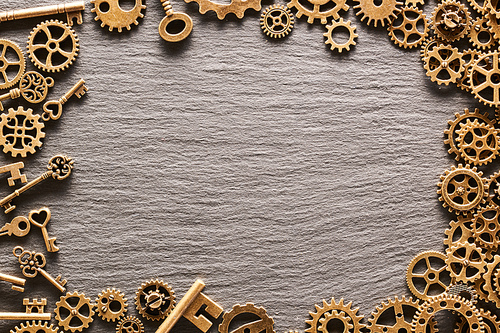 Various metal cogwheels, gear wheels and keys over slate background