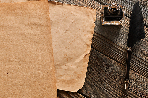 Feather pen and blank paper sheet over wooden background