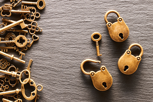 Various metal keys and locks over slate background