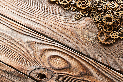 Various metal cogwheels and gear wheels over wooden background