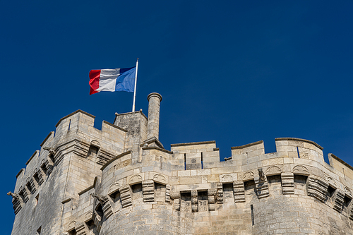 the French flag flying high over the walls of an old fort in La Rochelle