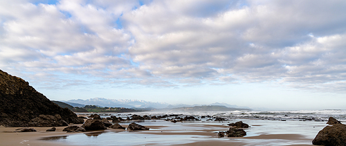 A panorama view of wild and rocky and sandy beach at low tide