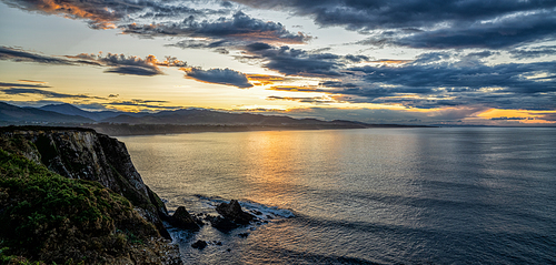 View of jagged and rocky ocean coast with cliffs at sunset