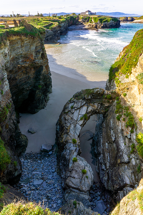 A warm golden evening on a sandy beach with jagged and rugged cliffs