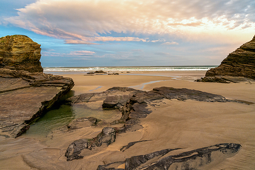 A beautiful beach with fine sand and rocky cliffs at sunrise