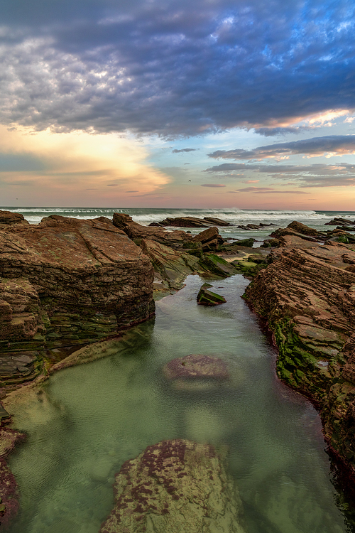 Beautiful sunrise at the Playa de las Catedrales Beach in Galicia in northern Spain with tidal pools in the foreground