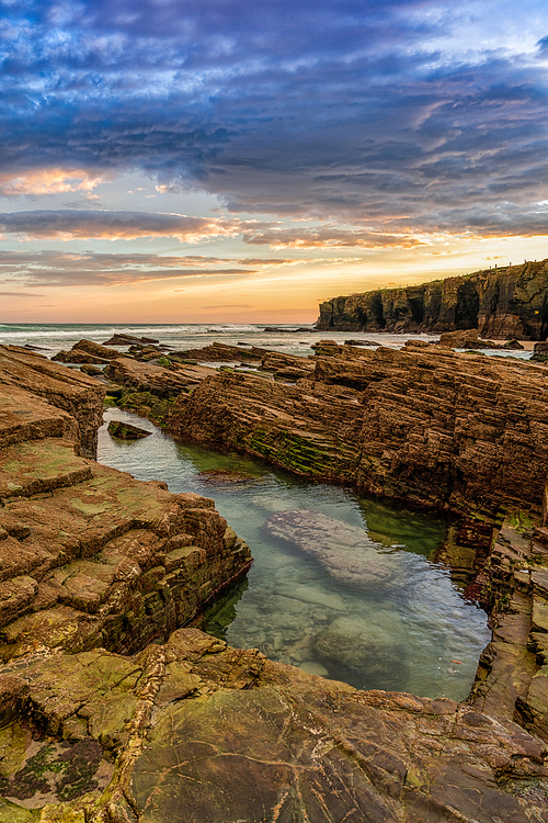 Beautiful sunrise at the Playa de las Catedrales Beach in Galicia in northern Spain with tidal pools in the foreground