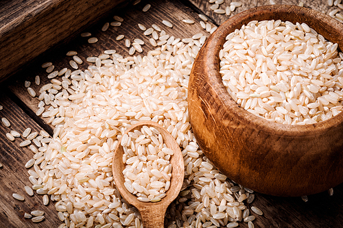 Rice in wooden bowl and spoon with grain