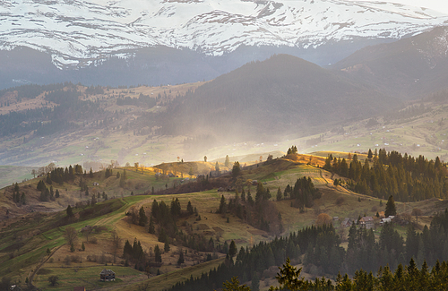 Evening light in spring carpathian mountains. Snow and green fields