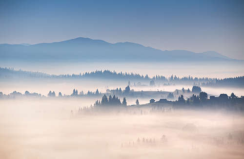 Autumn foggy morning in Carpathian mountains. Alpine village on the hills