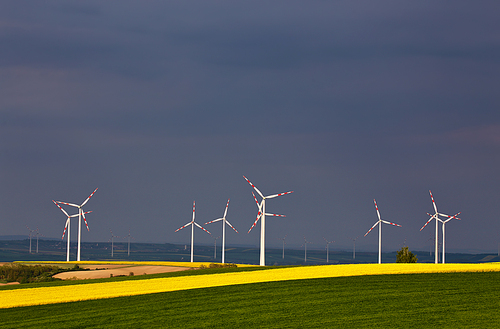 Green and yellow fields with Wind turbines generating electricity. Wind turbines before the thunderstorm. Spring sunny day on green field with wind power generators in Austria