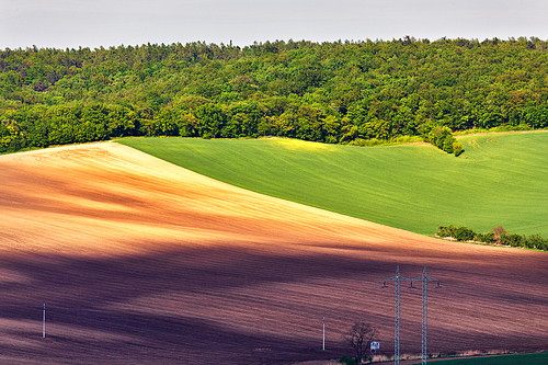 Green and brown spring ploughland. Rolling arable fields in Czech Moravia.