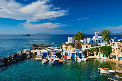 Typical Greece scenic island view - small harbor with fishing boats in crystal clear turquoise water, traditional white houses church. Mandrakia village, Milos island, Greece.