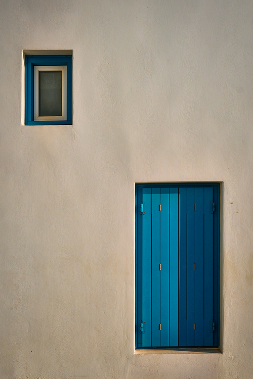 Greek architecture abstract background - whitewashed house with blue painted window blinds. Milos island, Greece