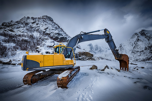 Old excavator with excavator bucket in winter. Road construction in snow. Lofoten islands, Norway. High dynamic range HDR image