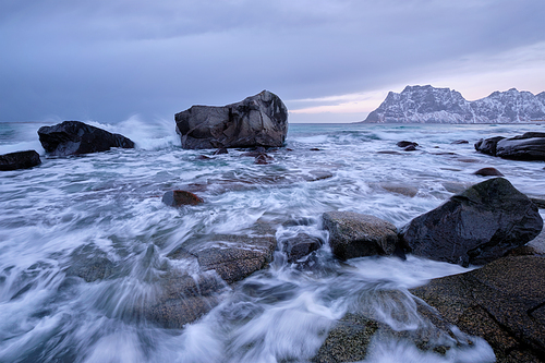 Rocks on beach of fjord of Norwegian sea in winter on sunset. Utakliev beach, Lofoten islands, Norway