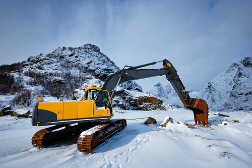 Old excavator with excavator bucket in winter. Road construction in snow. Lofoten islands, Norway