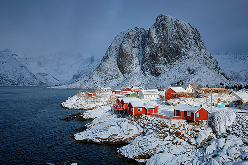 Iconic Hamnoy fishing village on Lofoten Islands, Norway with red rorbu houses. With falling snow in winter.