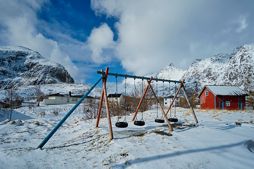 Children playground with swings made of car tires in winter. A village, Lofoten islands, Norway