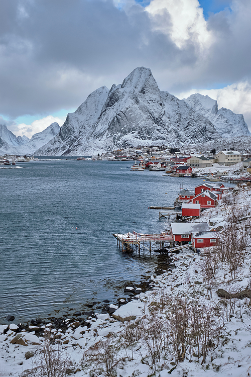 Reine fishing village on Lofoten islands with red rorbu houses in winter with snow. Norway