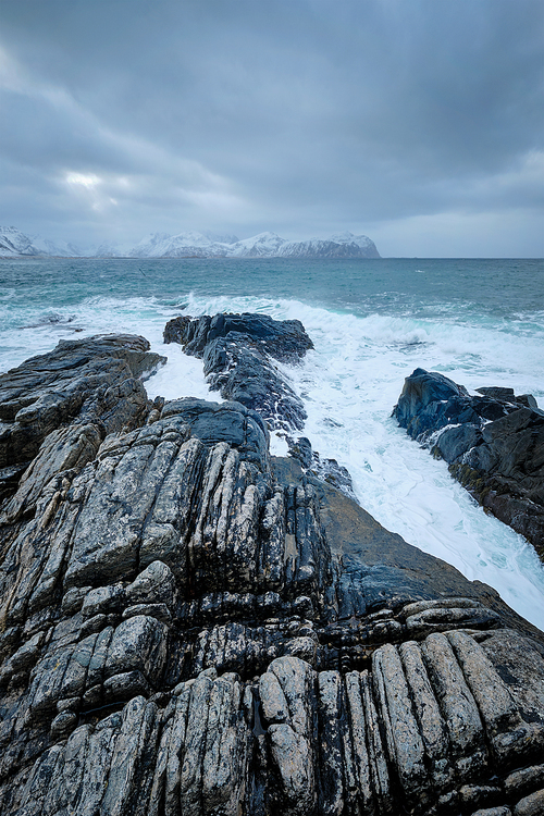 Waves of Norwegian sea crushing at rocky coast in fjord. Vikten, Lofoten islands, Norway