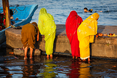 Indian women doing morning pooja on ghats of sacred Narmada river. Maheshwar, Madhya Pradesh, India
