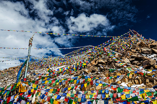 Tibetan prayer flags of Buddhism with Buddhist mantra on it on top of Himalayan pass Khardung La. It
