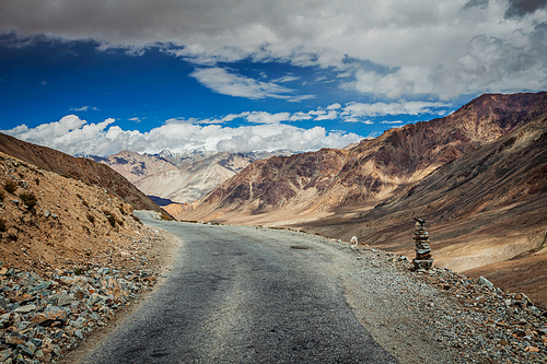 Road in Himalayas near Kardung La pass with stone cairn. Ladakh, India