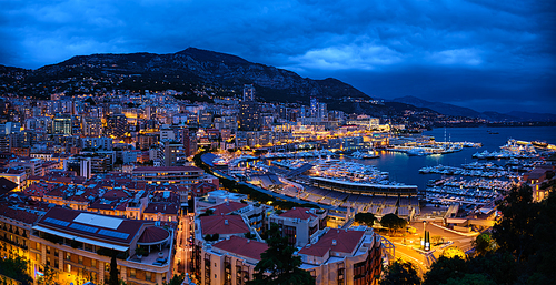 Aerial panorama of Monaco Monte Carlo harbour and illuminated city skyline in the evening blue hour twilight. Monaco Port night view with luxurious yachts