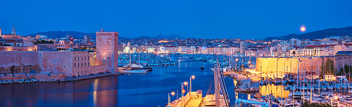 Panorama of Marseille Old Port and Fort Saint-Jean illumintaed in night with moon. Marseille, France. Marseille, France. Horizontal camera pan