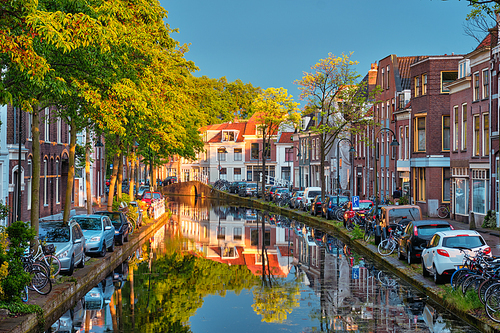 Delt canal with old houses and cars parked along on sunset. Delft, Netherlands
