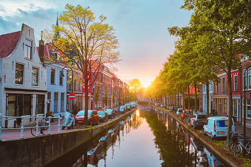 Delt canal with old houses and cars parked along on sunset. Delft, Netherlands