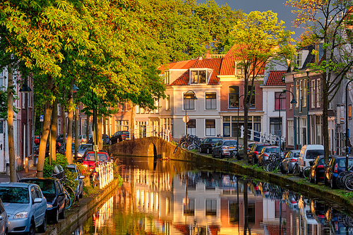 Delt canal with old houses and cars parked along on sunset. Delft, Netherlands