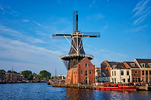 Harlem cityscape - landmark windmill De Adriaan on Spaarne river with boats. Harlem, Netherlands